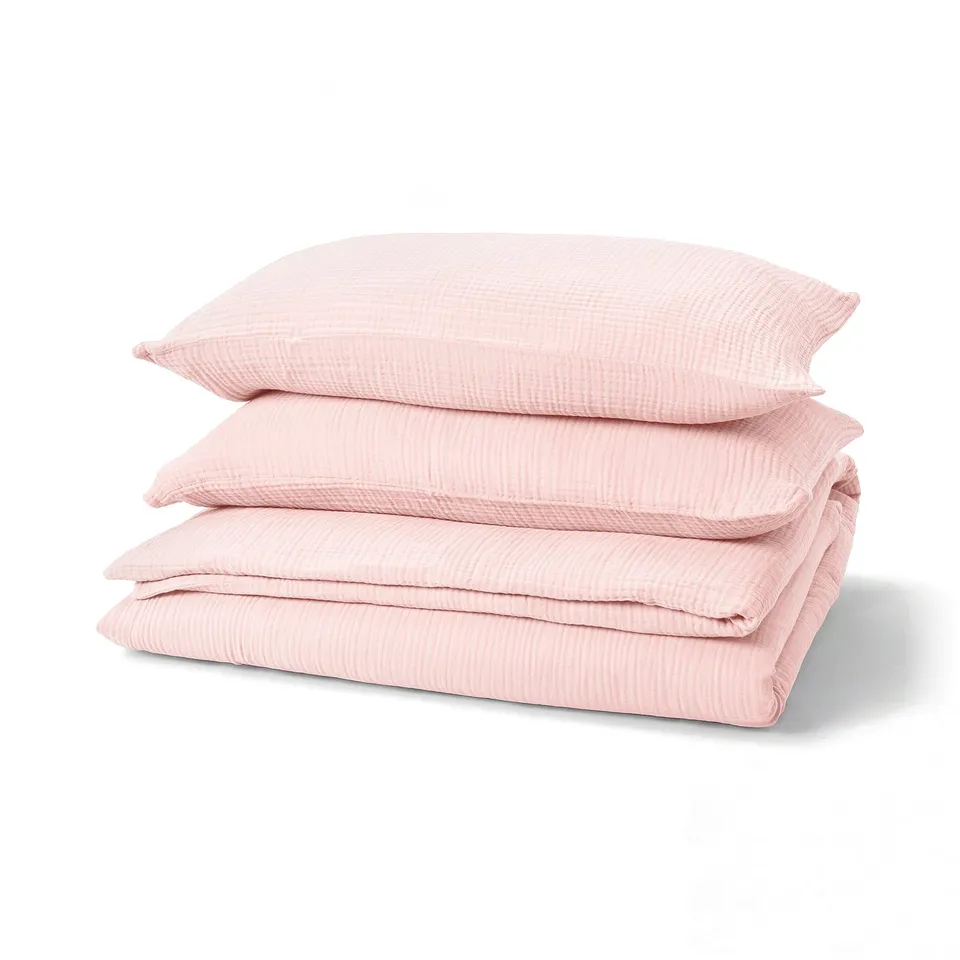 Pile of 4 pink organic cotton pillows, neatly folded, soft muslin texture.