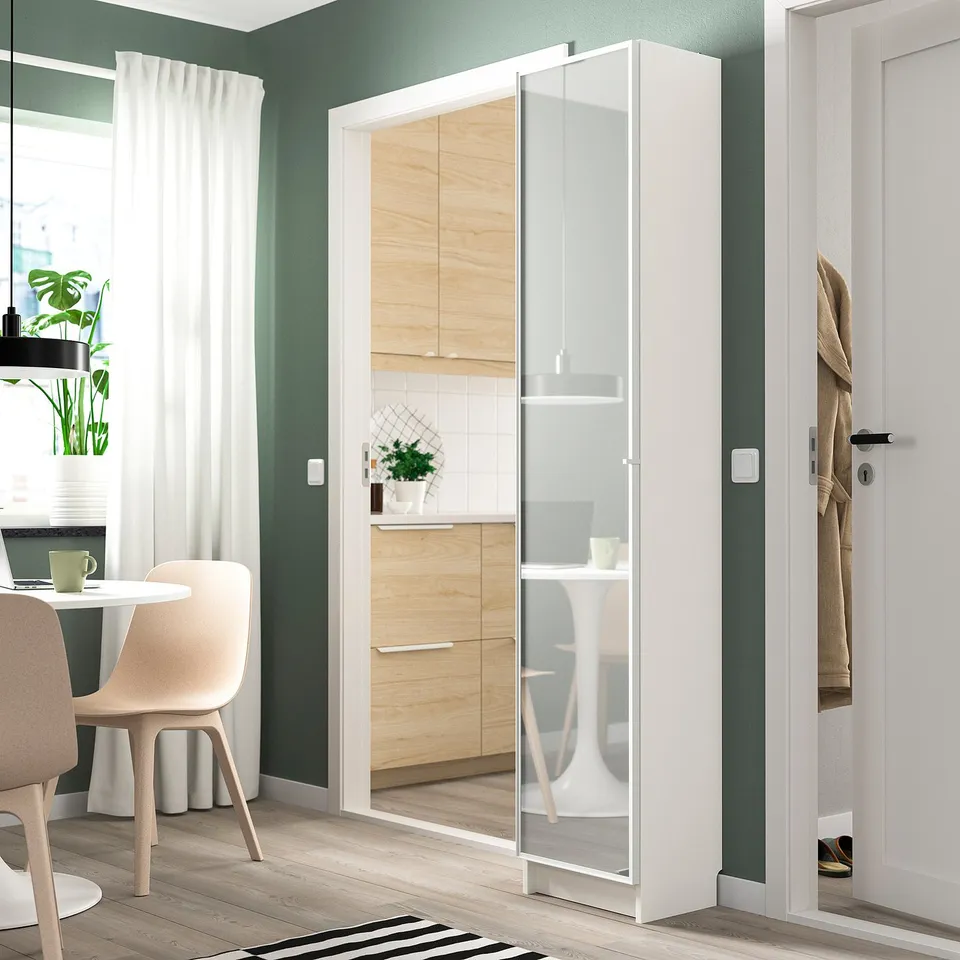 Modern apartment with white BILLY bookcase, dining area, and muted green walls.