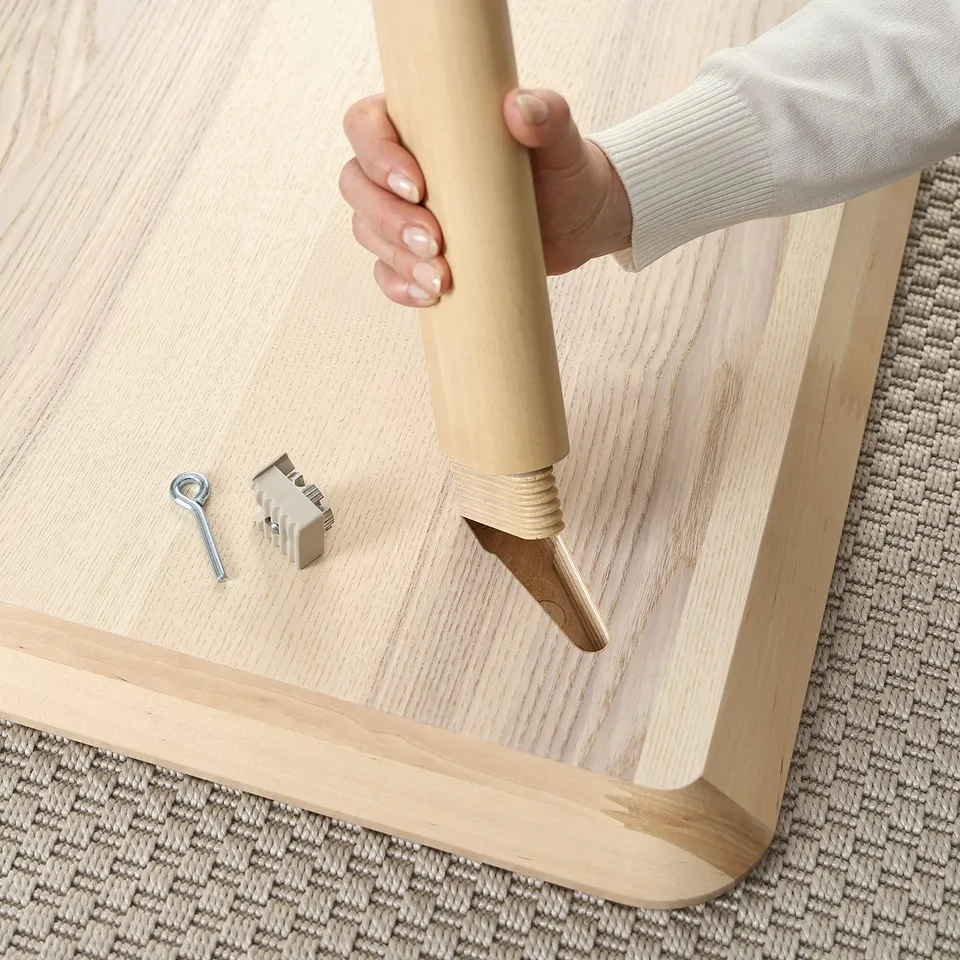 Person assembles wooden table with tools.
