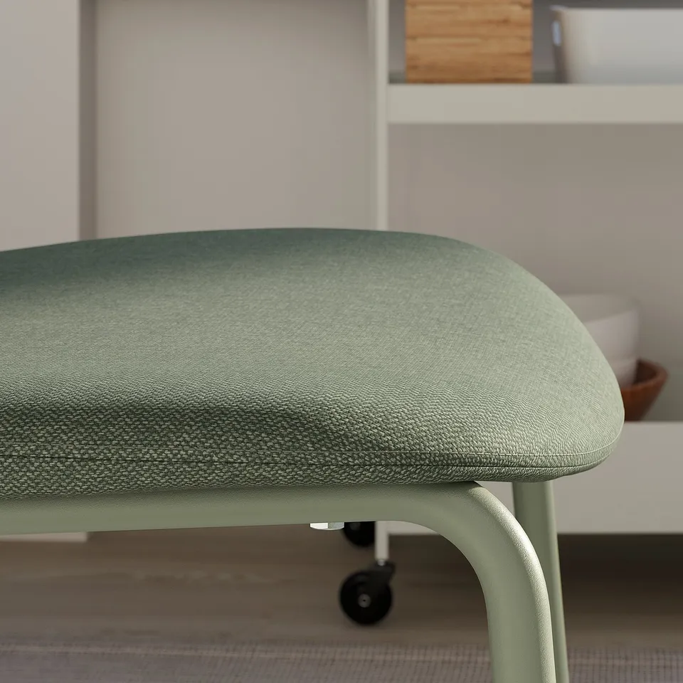 A close-up of a green upholstered chair seat, showcasing its soft padding and sturdy frame.