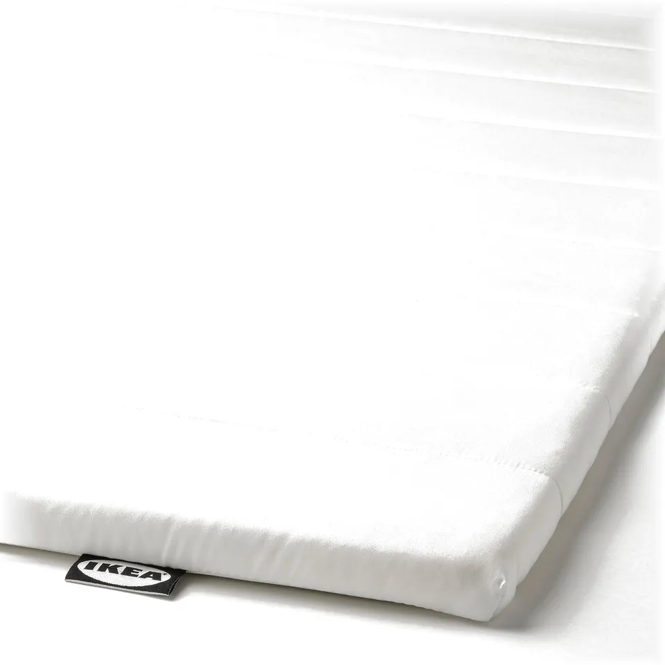 White mattress pad with textured surface, smooth fabric, and embroidered ikea label on corner.