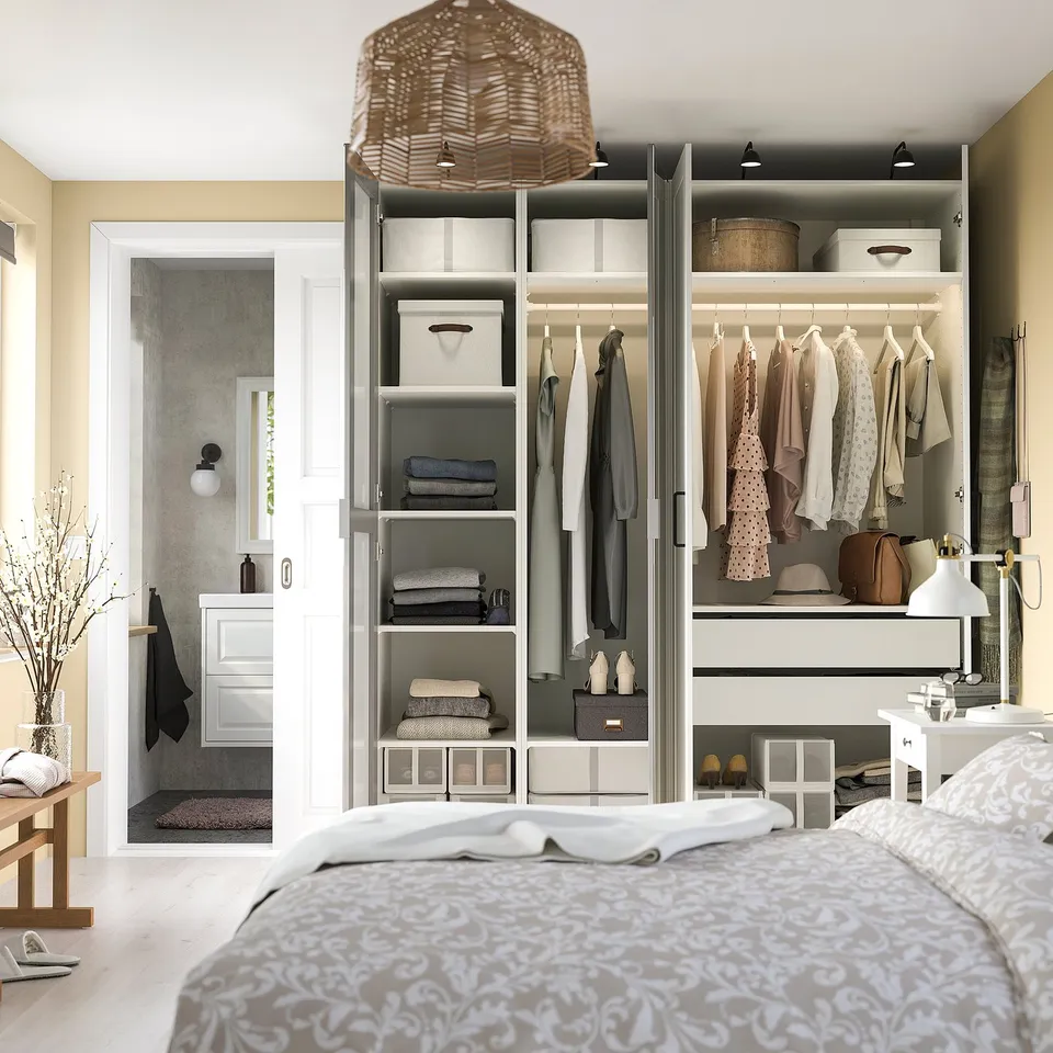 Bedroom with grey bed, large PAX wardrobe, folded clothes, and lighting.