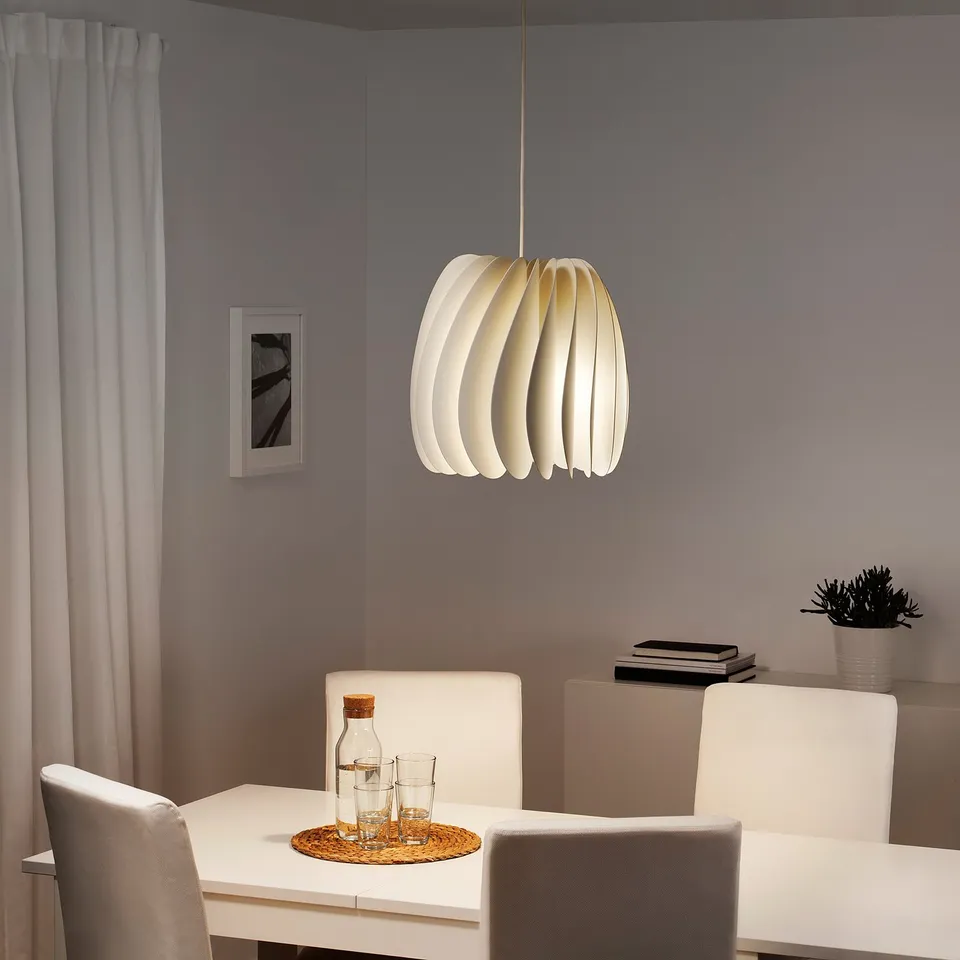 Modern dining with SKYMNINGEN lamp over white table and chairs, grey walls.