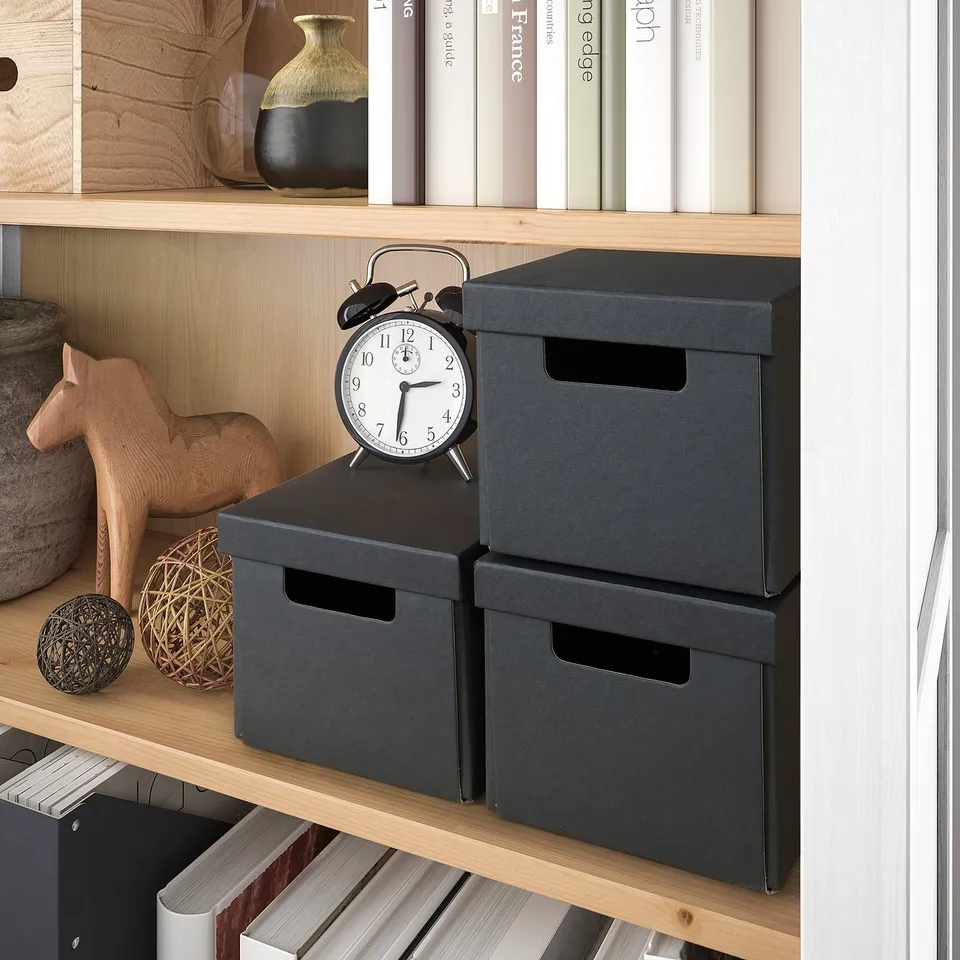 Shelf with boxes, clock, and decor. Holds items neatly.