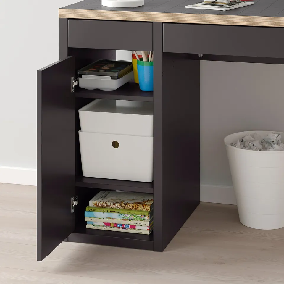 Black desk with open cabinet showing storage boxes, books, and supplies.