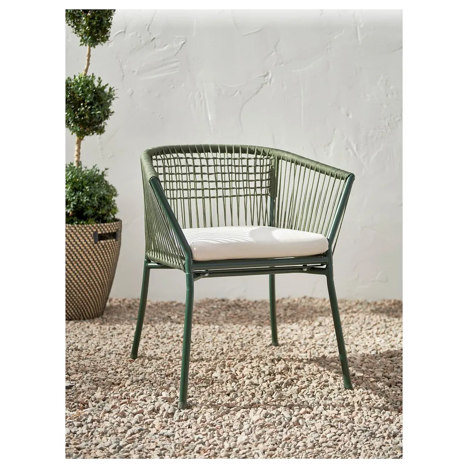 Green outdoor chair, woven design, armrests, textured cushion, against white wall.