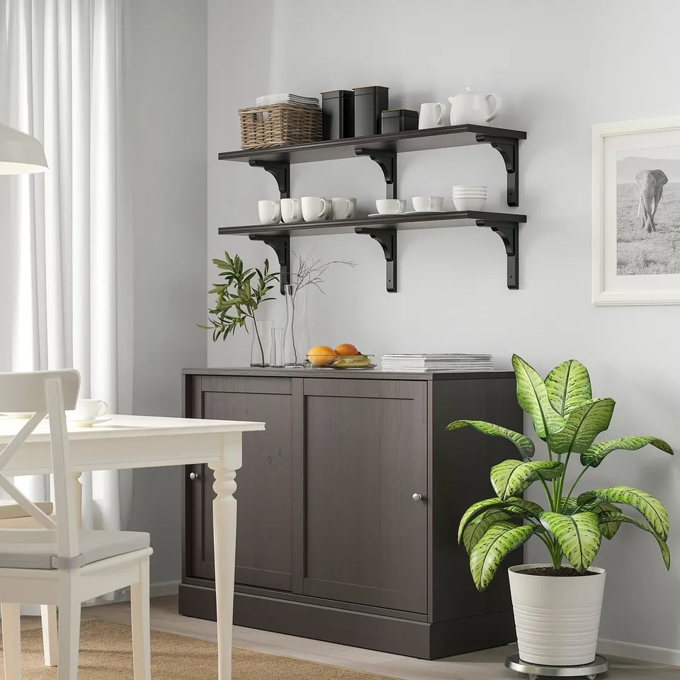 Modern dining room with dark shelves, decor, plant, and art.