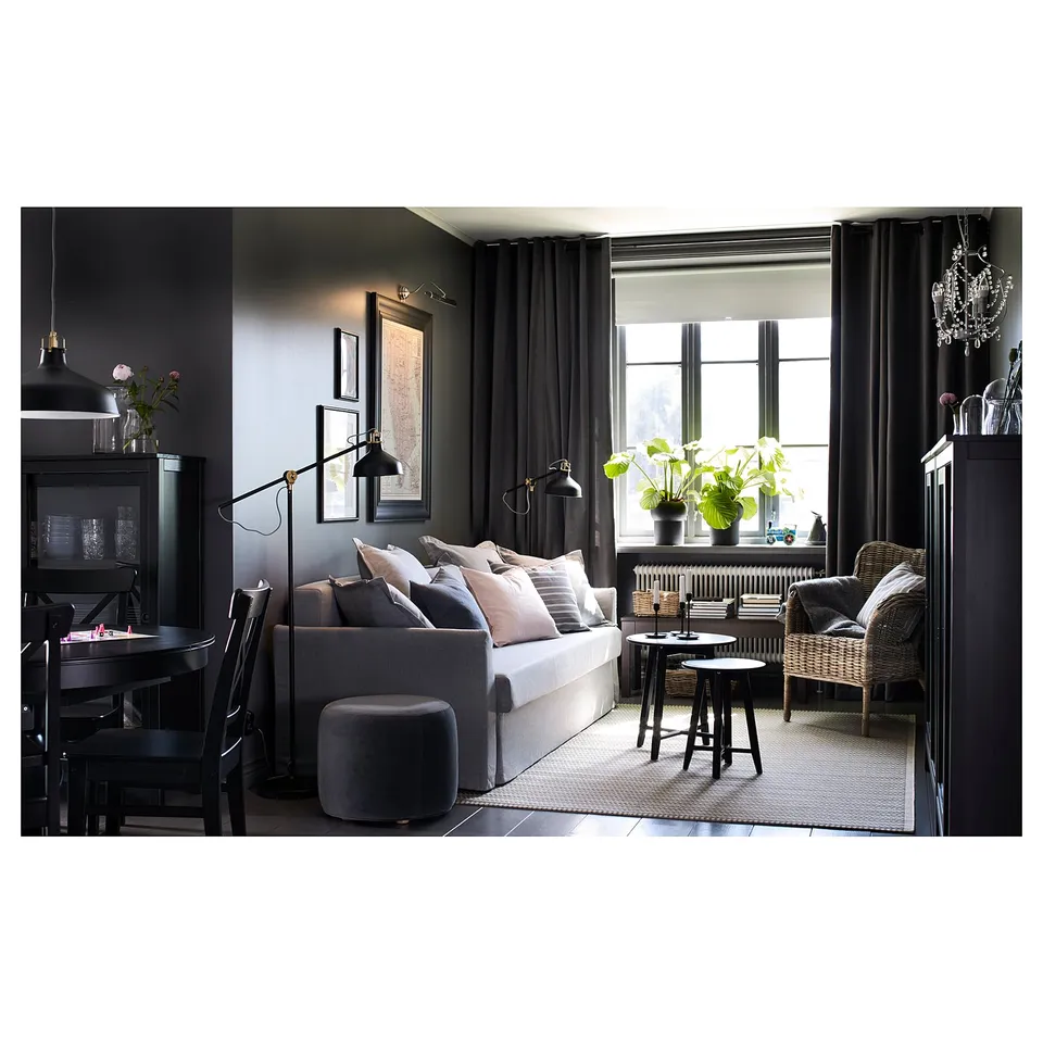 Cosy modern living room with grey KRAGSTA tables, sofa, and wicker chair. Dark walls and large windows.