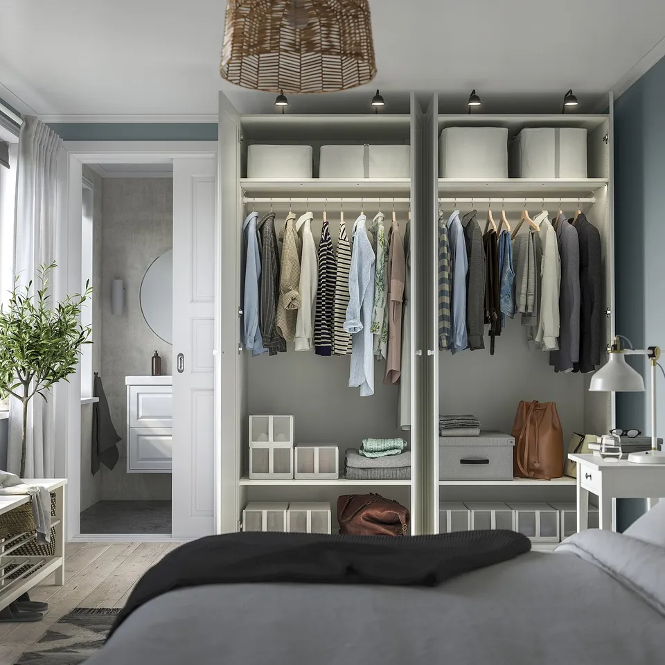 Bedroom with open wardrobe showing clothes, storage boxes, and adjustable lighting.