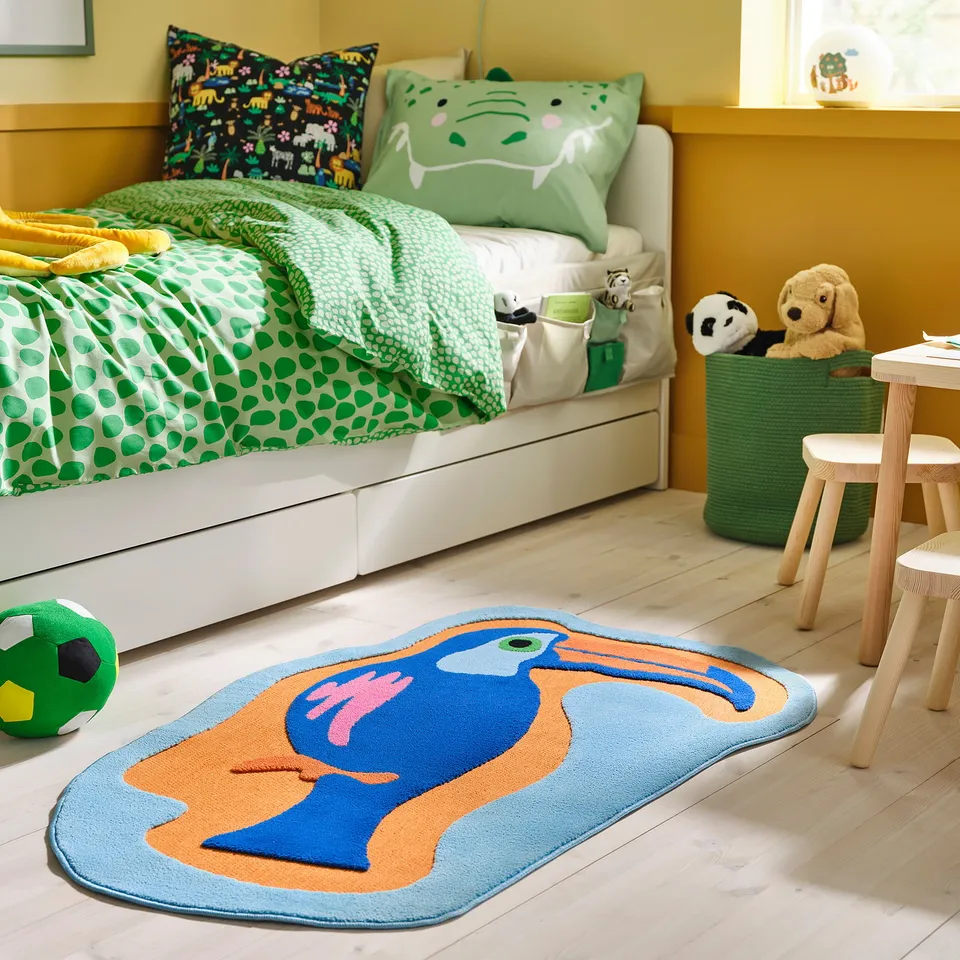 Kids room with colourful toucan rug, green bedding, and stuffed animals.