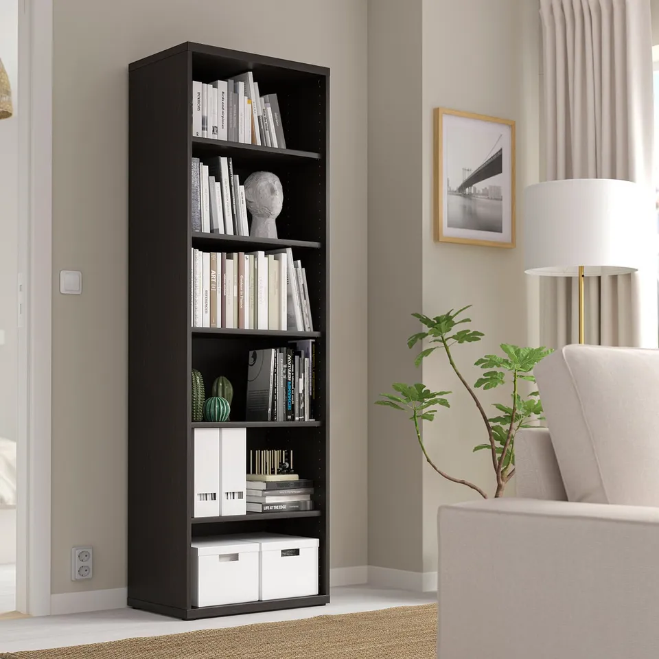 Black BESTÅ bookshelf with books and decor in modern living room.