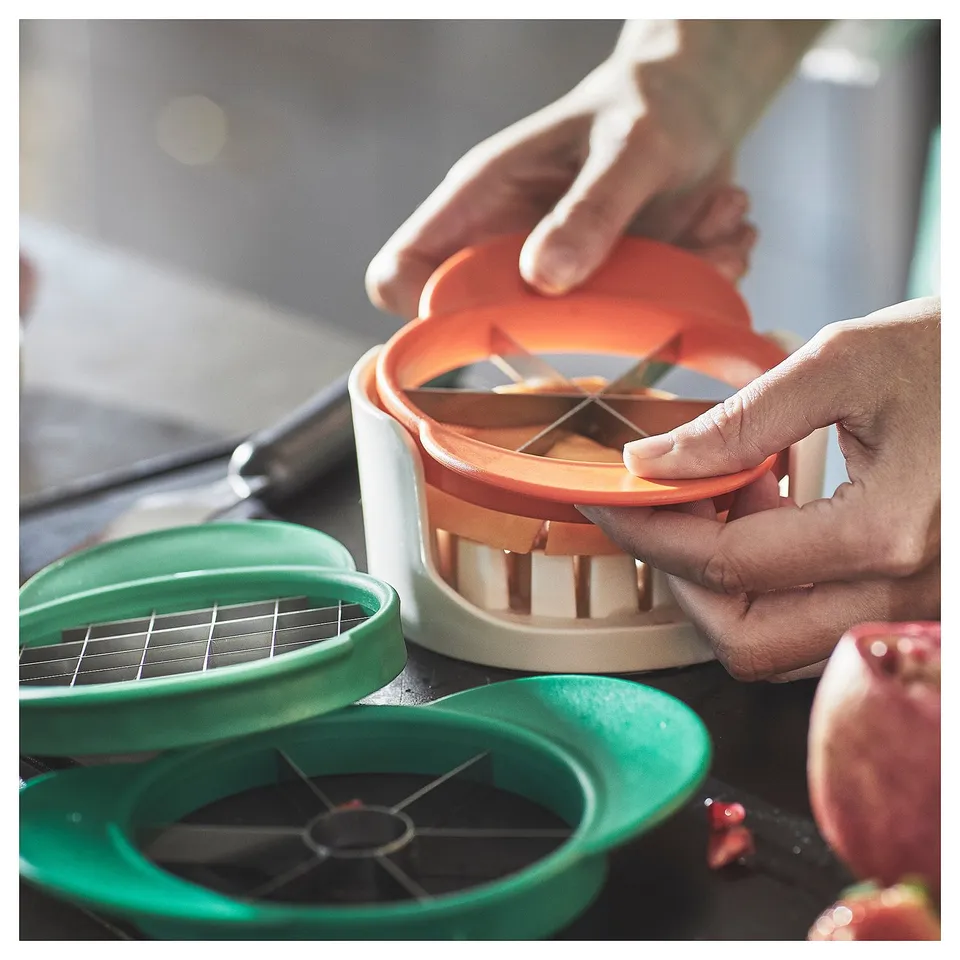 Person using orange UPPFYLLD fruit slicer on counter.