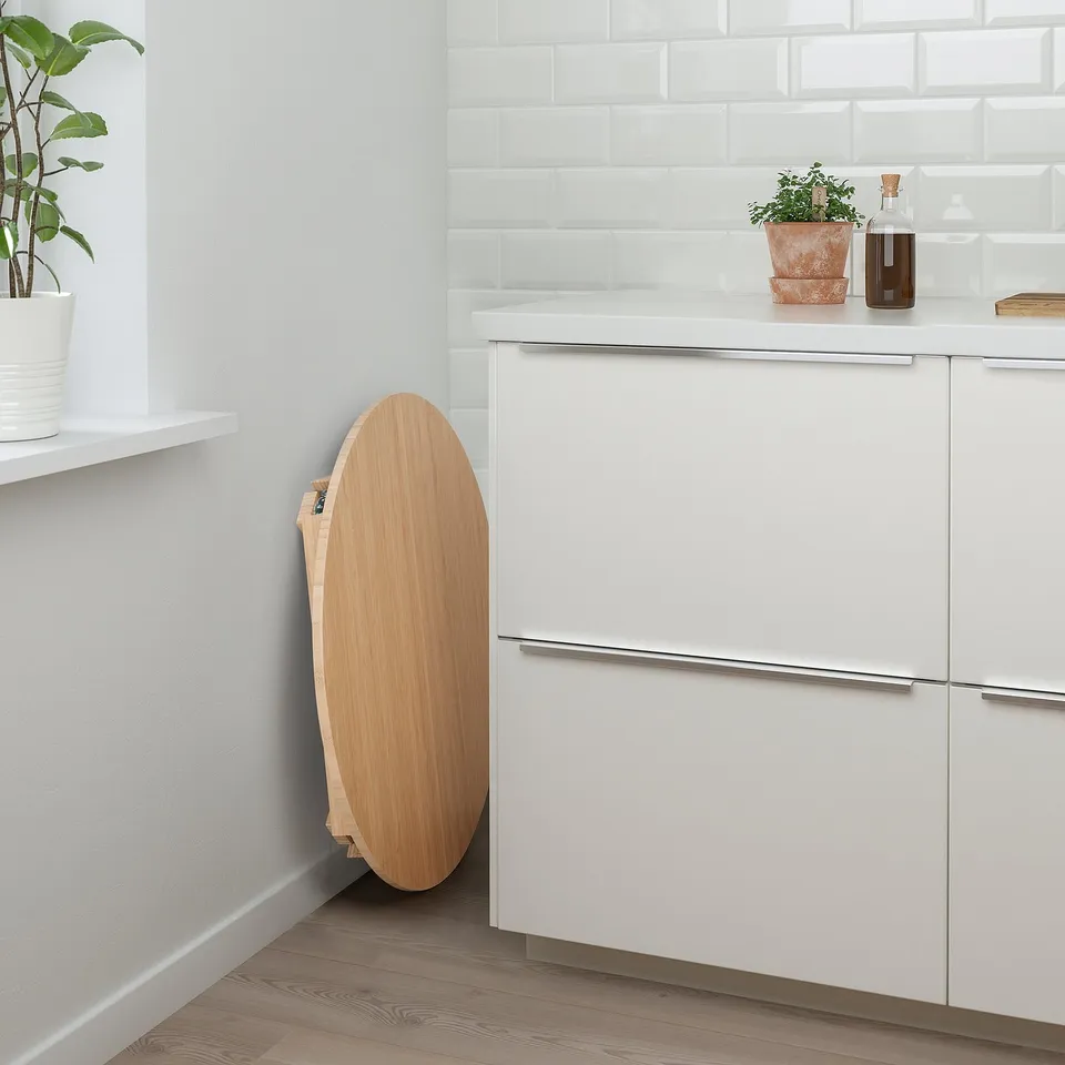 Modern kitchen with white cabinets and a bamboo MOXBODA folding table against them.