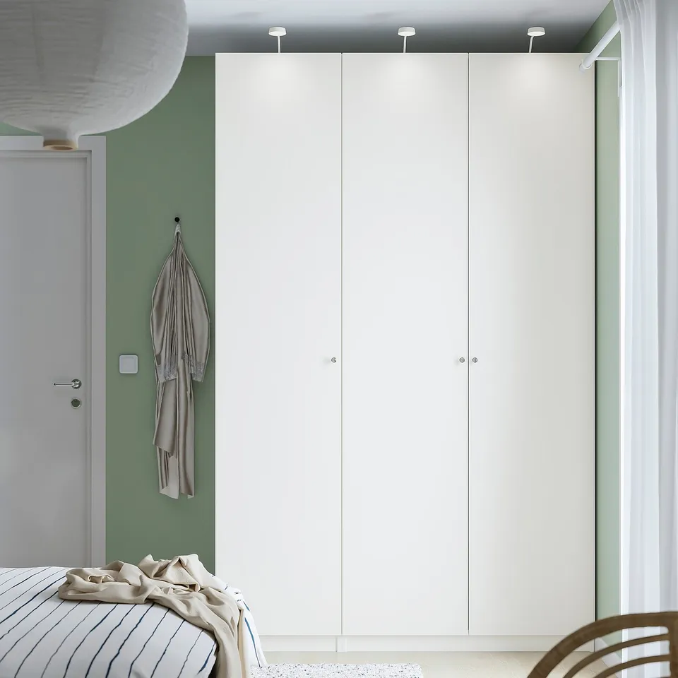 Minimalist bedroom with large white PAX wardrobe, light green walls, and striped bedding.