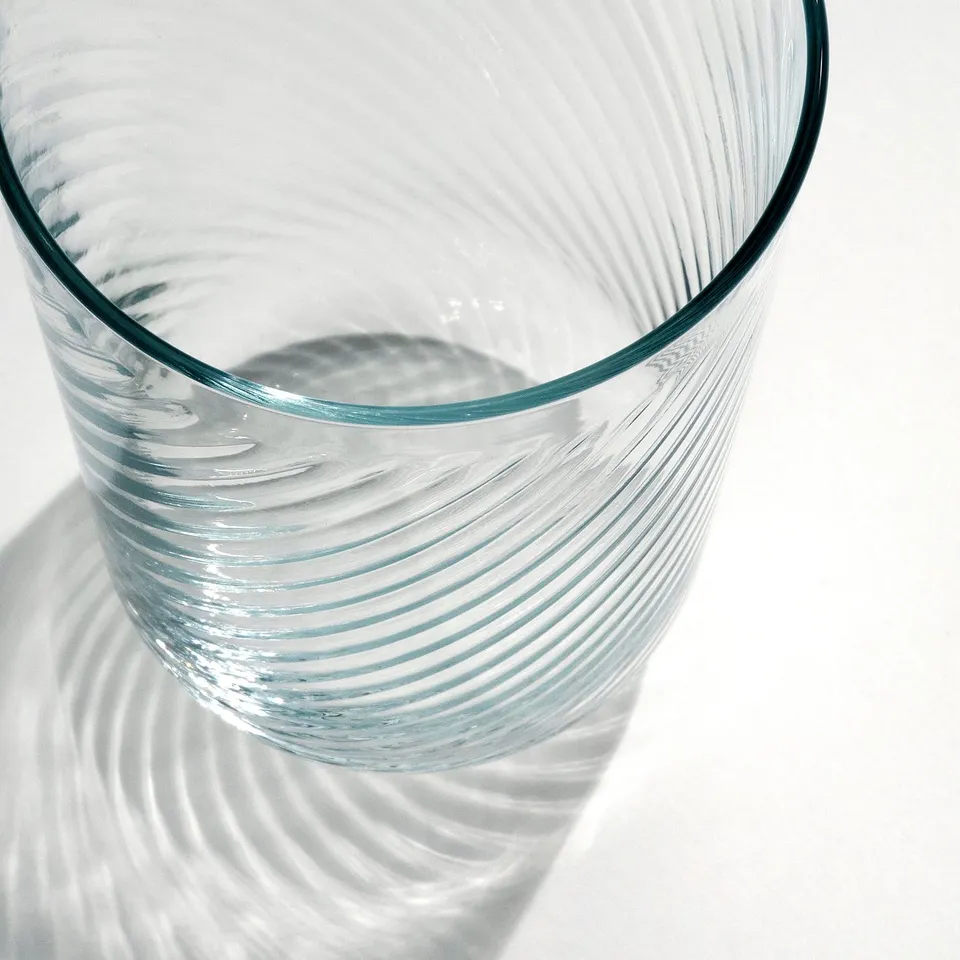 Elegant, thin glass with rippled design. Lit from above, casting swirling shadows.