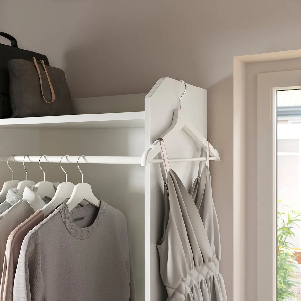 Closet with clothes; white, wooden; organised; hangers visible; soft lighting.