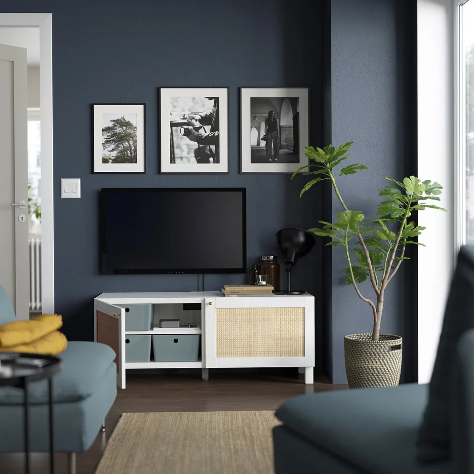 Modern living room: dark walls, BESTÅ tv, blue seats, plant.