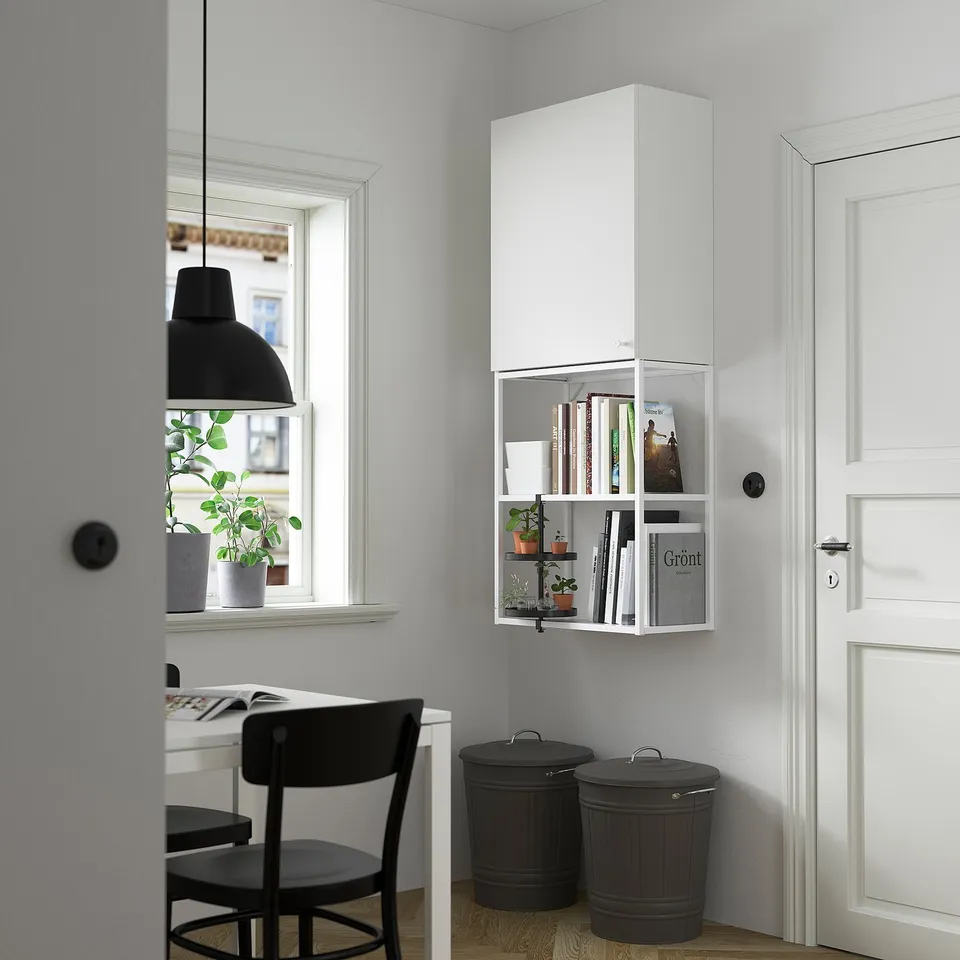 Modern minimalist room with white ENHET wall cabinet and shelves, black furniture, and plants.