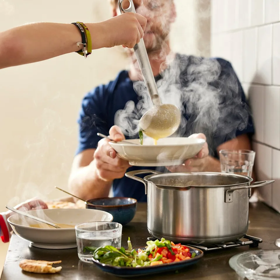 Cooking with strainer, steam rising. Alternatively, for a more concise version: cooking with strainer.