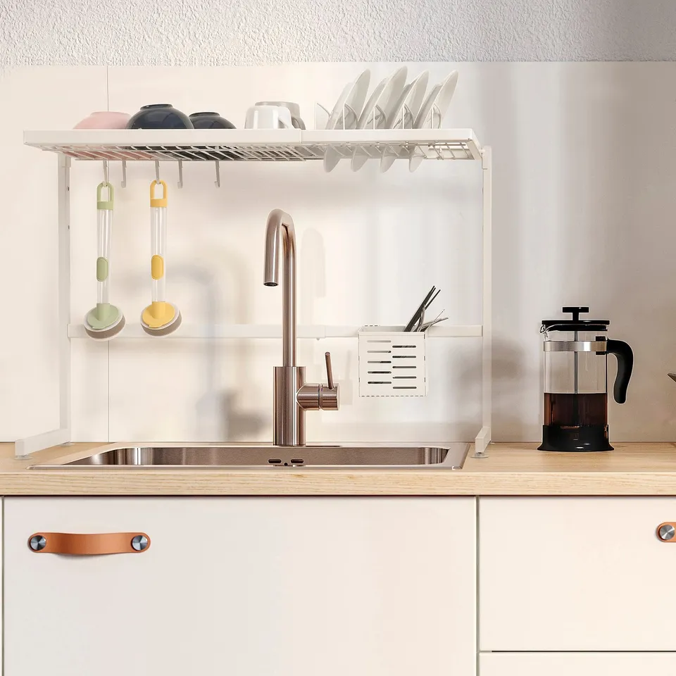Over-sink dish drainer with adjustable size, holding dishes and cutlery, freeing counter space.
