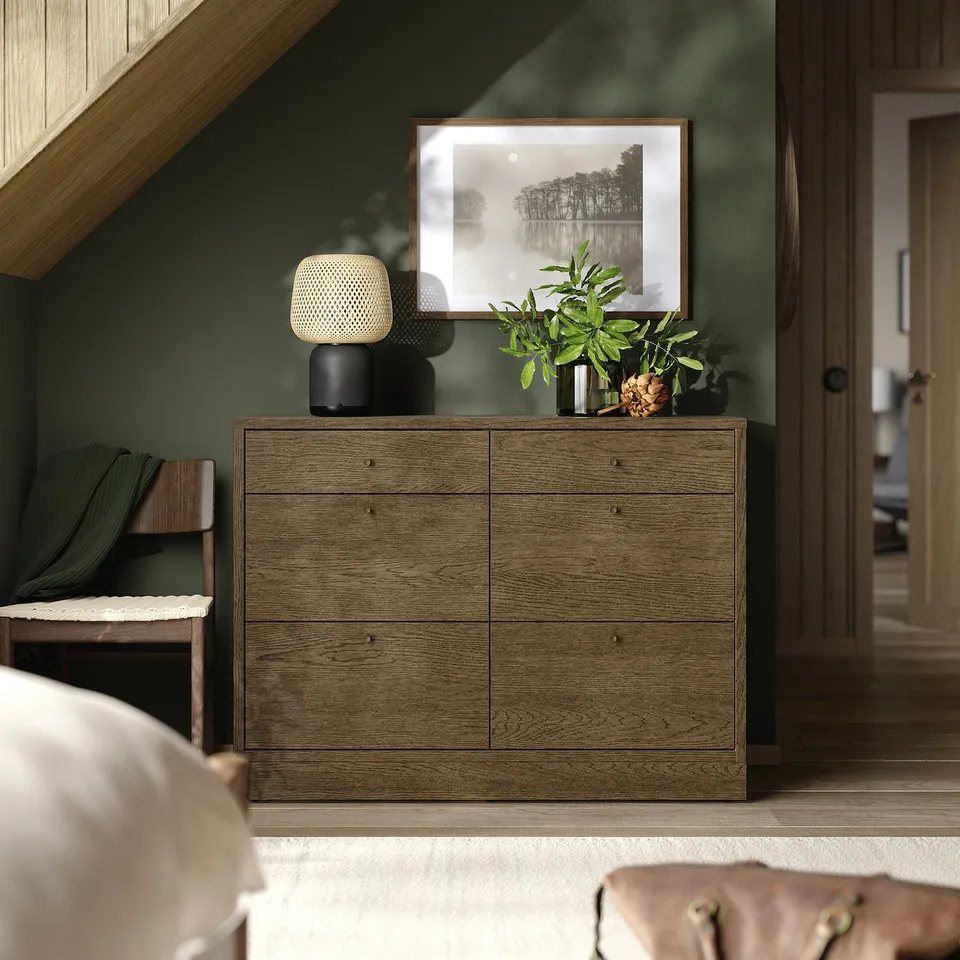 Modern bedroom with TONSTAD oak drawers, white lamp, green wall, large photo, plant, and chair.