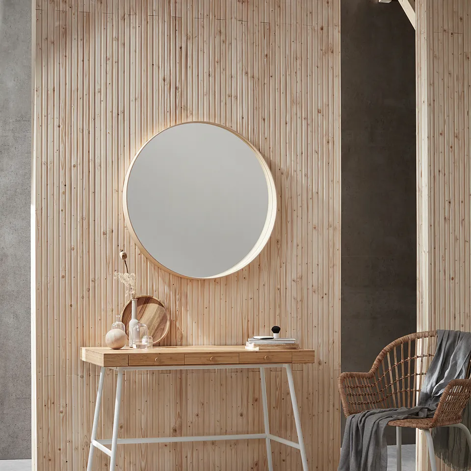 Modern minimalist desk, LILLÅSEN, light wood, round mirror, wicker chair, grey rug, concrete walls.