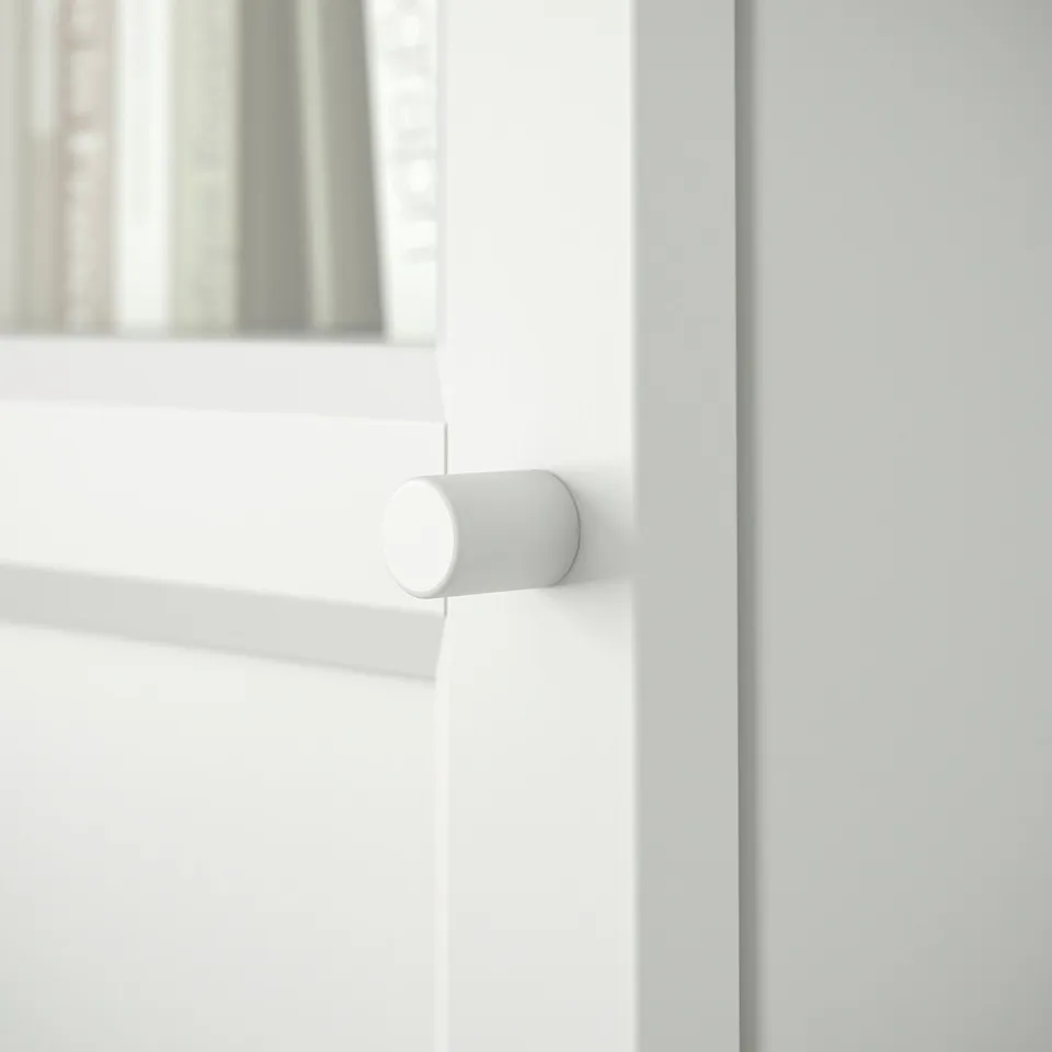 A close-up of a white BILLY bookcase door handle; smooth, cylindrical design.