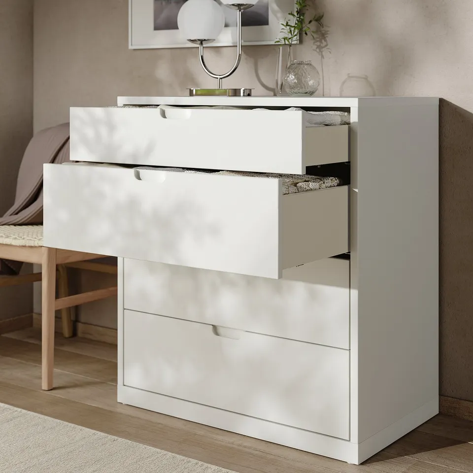 White TONSTAD chest with four open drawers in a modern bedroom featuring light wood floor and neutral decor.