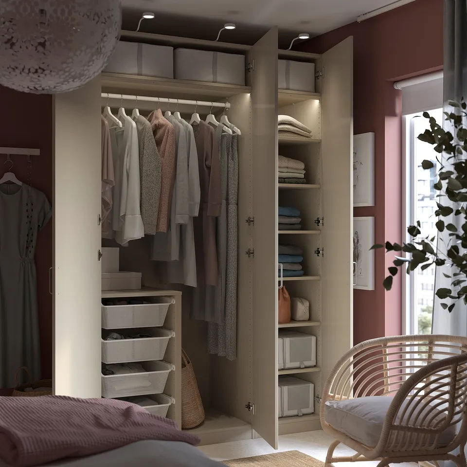 A well-organized PAX closet hanging clothes, shelves with folded clothes, and storage baskets. Soft lighting illuminates the interior.