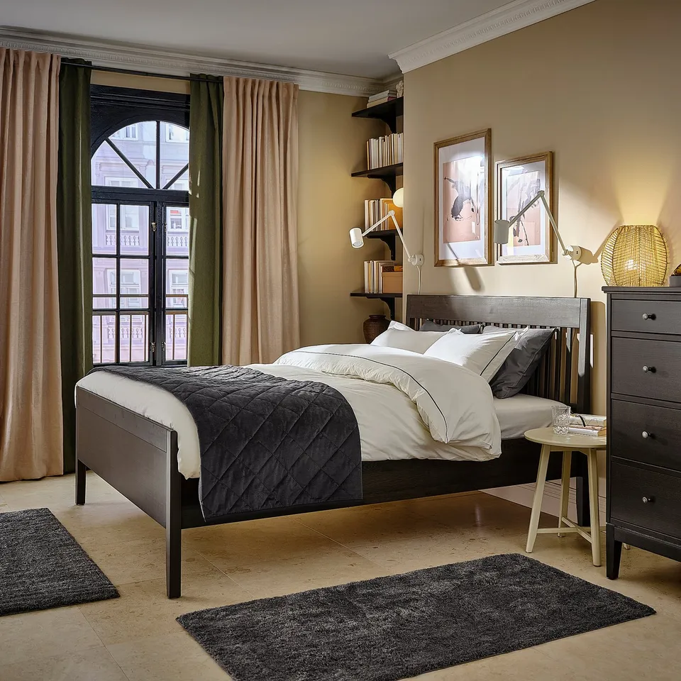 Modern bedroom with IDANÄS bed, black & white linens. Wooden headboard, black veneer, beige walls. Balcony view.