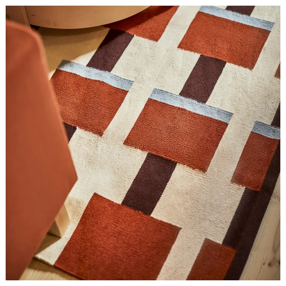 Handwoven orange and beige wool rug with geometric squares, ultra-soft texture, reversible and versatile for living spaces.