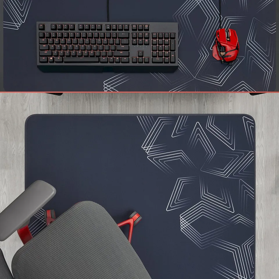 A gaming setup featuring a keyboard, mouse, and chair castor protector on a dark desk with a geometric-patterned mat.