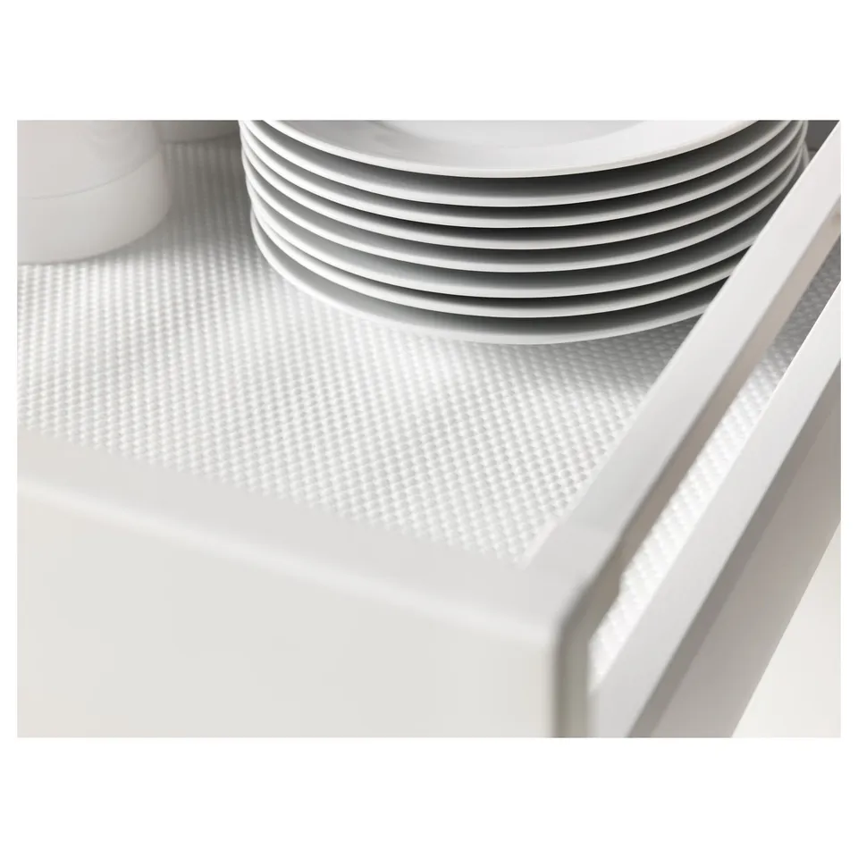 Stack of white plates on a textured drawer mat, reducing noise and preventing scratches.