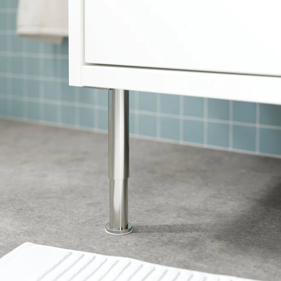 Metal leg supporting white cabinet, blue tile background.