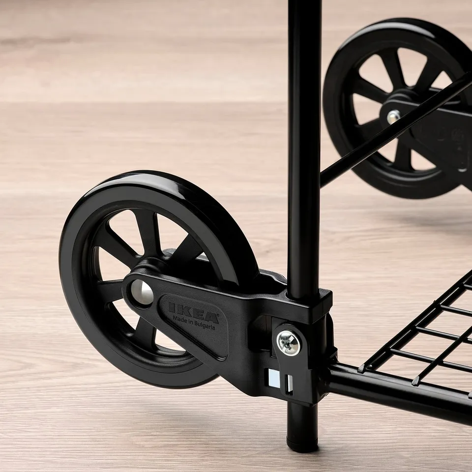 Close-up of a robust, black ikea wheel with a metal frame on a wooden floor.