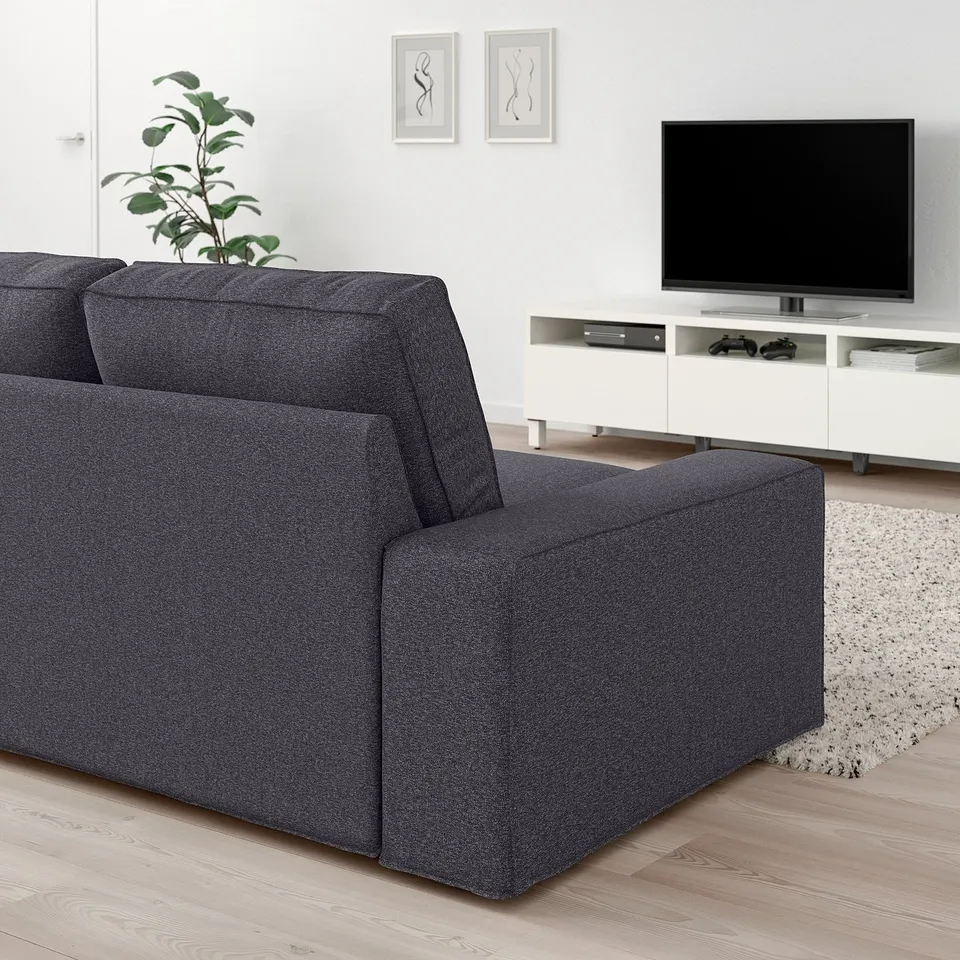 Modern living room: KIVIK dark grey fabric sofa, flat-screen tv, white console, green plant, & rug. Sofa is large & comfortable.