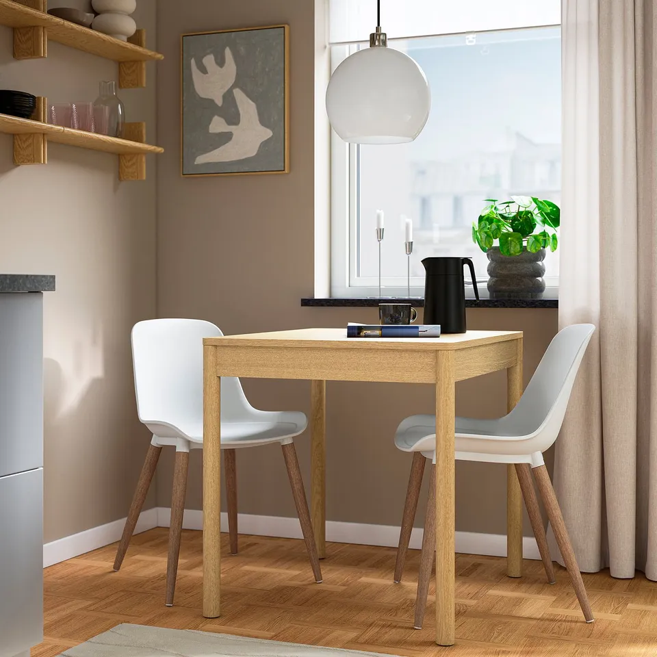 Small GRÖNSTA dining set with light wood & white plastic chairs, round table, near window.