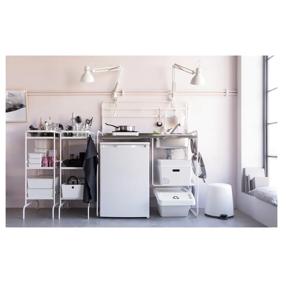 Compact mini-kitchen setup with white shelves, sink, and fridge. Adjustable lamps above, perfect for small spaces.