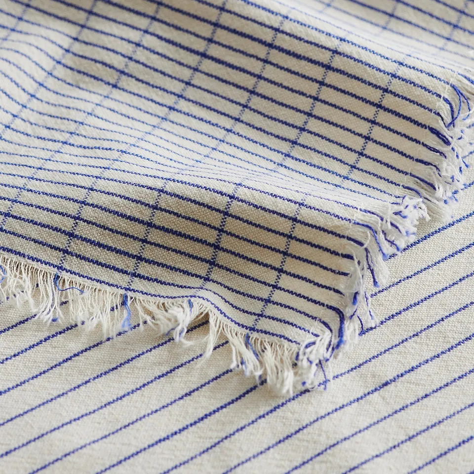 Close-up of VÄLVÅRDAD towel: cream background, blue stripes, fringes; shows texture & quality.