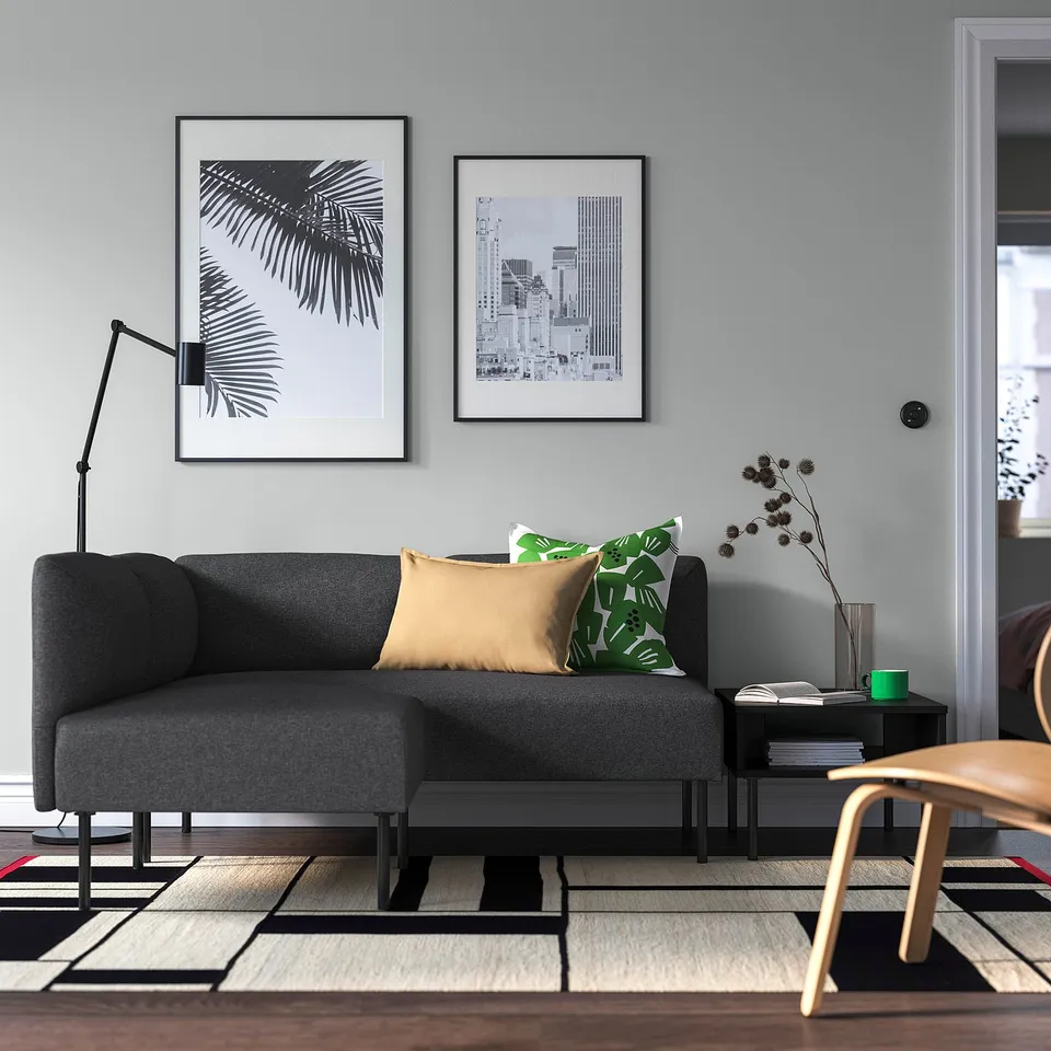 Modern living room: grey lillem sofa, black framed art, chic cushions, wooden chair, colourful rug.