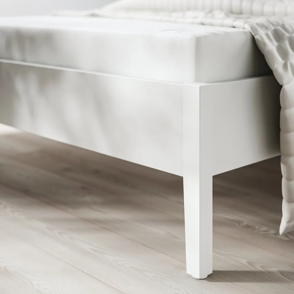 Clean, minimalist bed frame with sleek white finish, sturdy tapered legs, and smooth storage drawers.