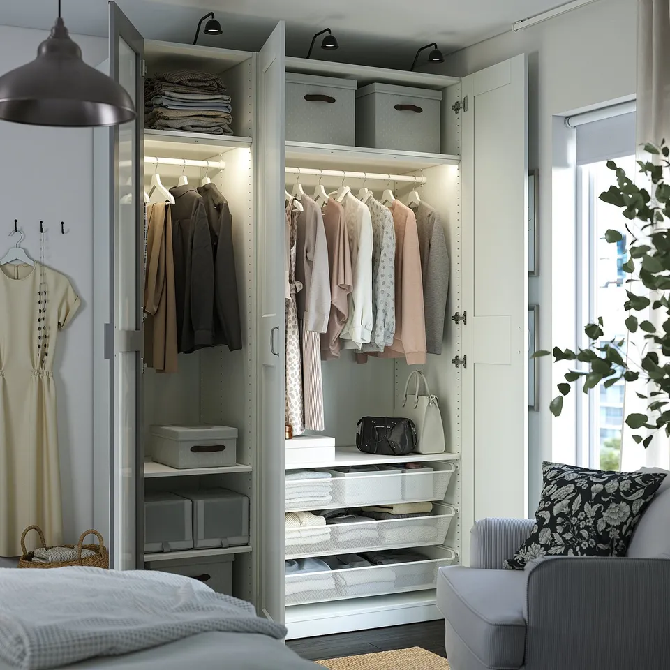 Organised walk-in closet with PAX system, neat clothes, storage boxes, and lighting.