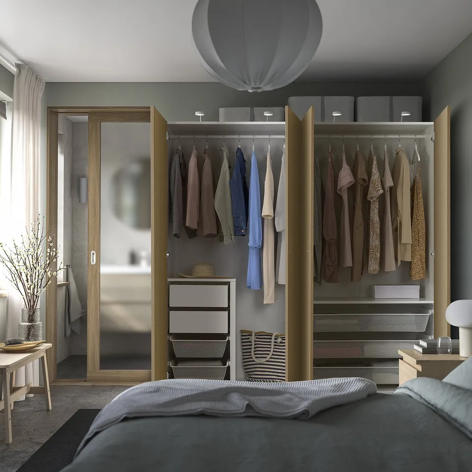Bedroom with open closet: clothes, drawers, shelves, lamp, plant, mirror.