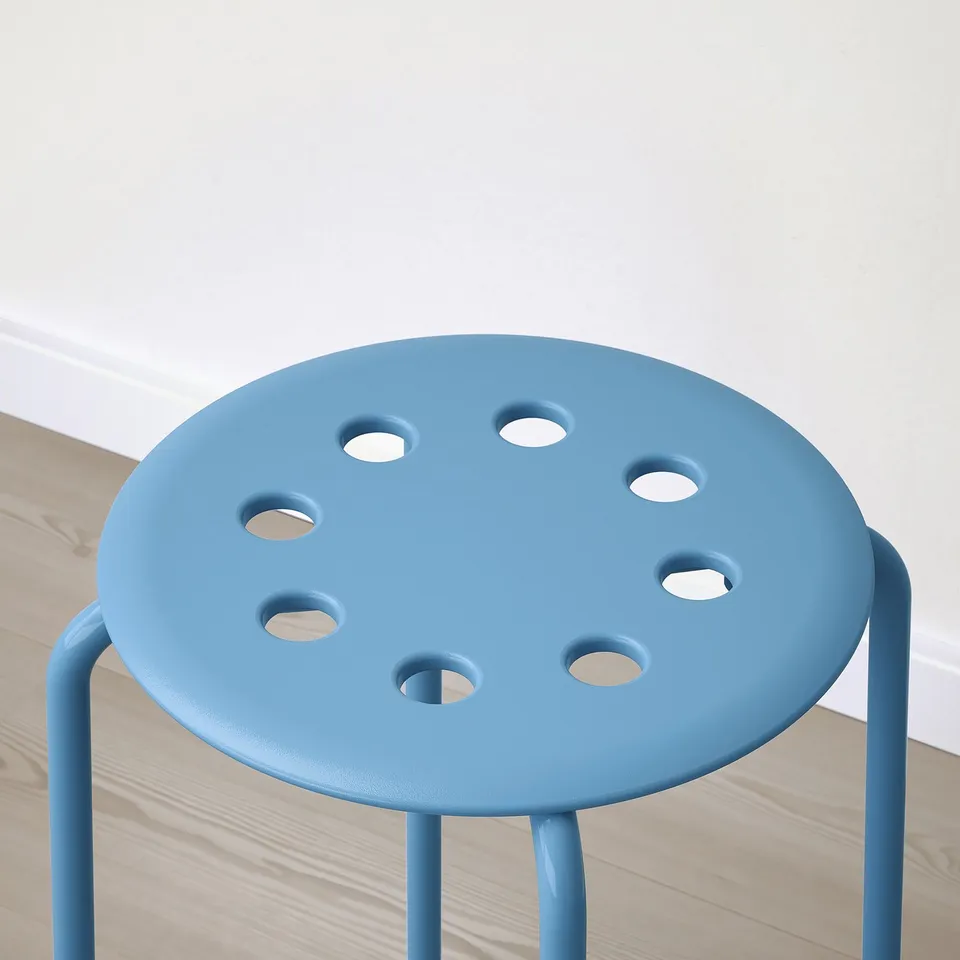 Blue stool with cutouts on wood floor.