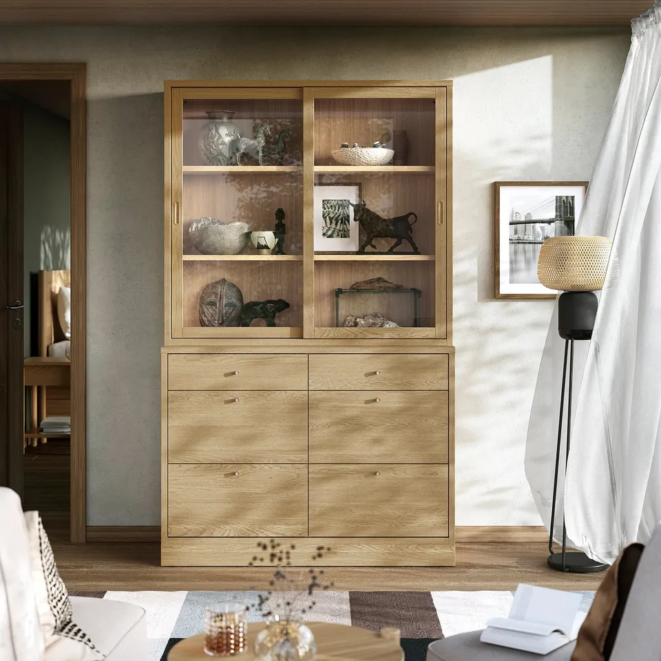 Minimalist living room with wooden cabinet, drawers, lamp, and white curtain.