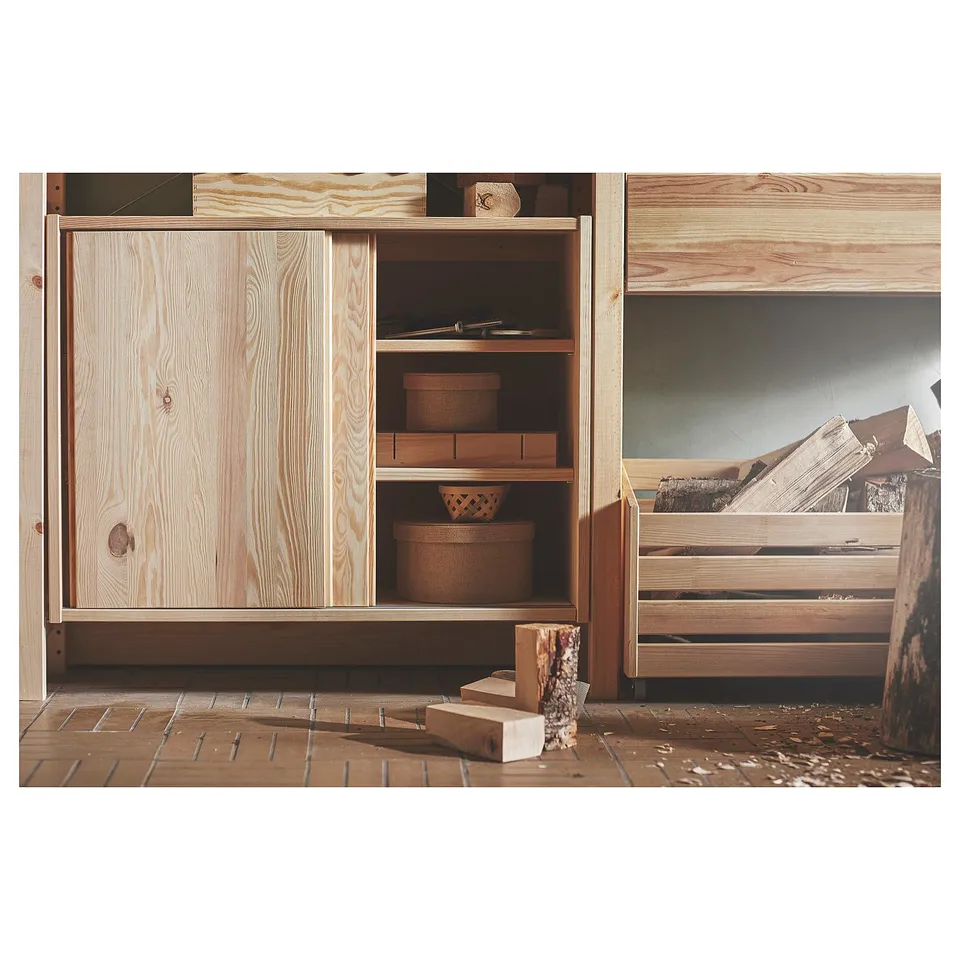 Natural wood IVAR storage unit with sliding door and woven baskets.