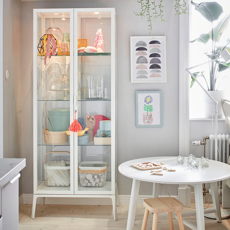 Modern kitchen with MILSBO glass cabinet, colourful items, adjustable shelves, and lock.