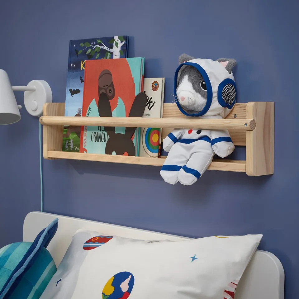 Childs blue room: bed, books, astronaut toy.