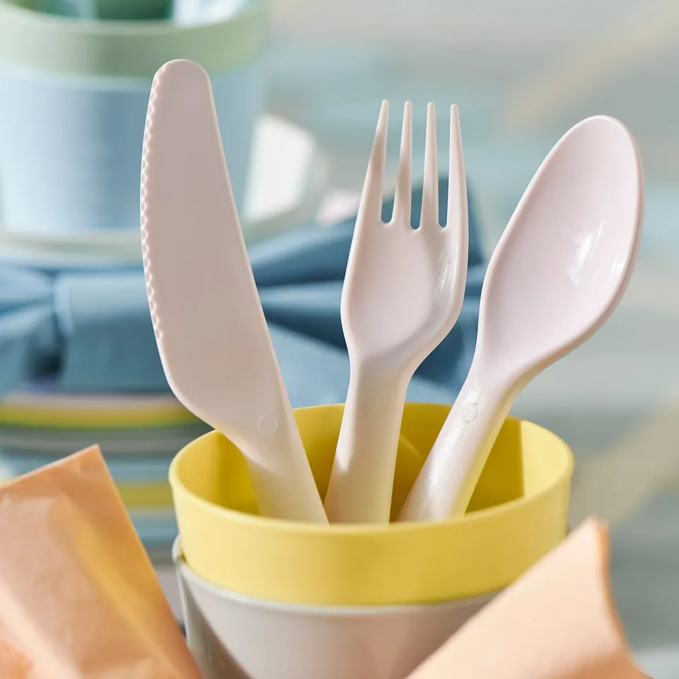 Colourful kids utensils: knife, fork, spoon in yellow container, easy grip.