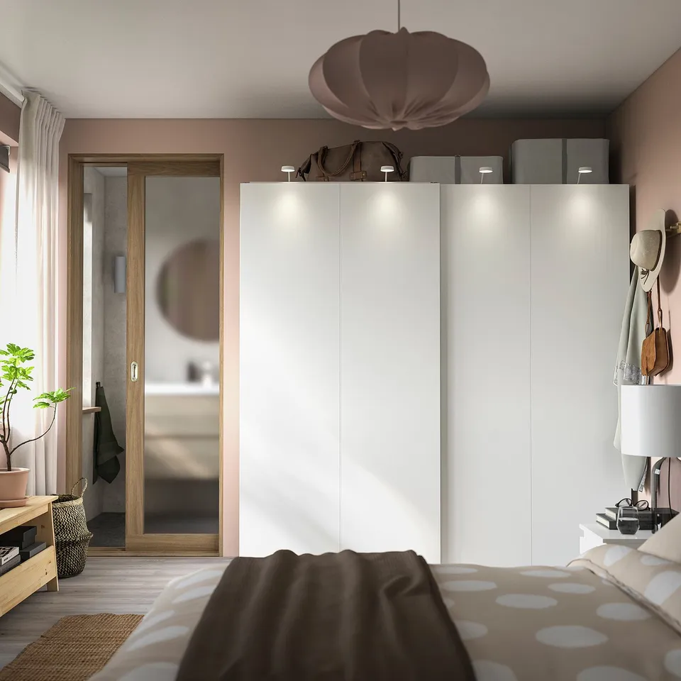 Modern bedroom with white HASVIK wardrobe, mirror, polka dot bedding, pendant lamp, and plants.